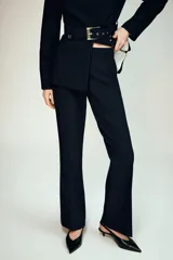 Pantalón de tiro medio con corte flare y bajo evasé. Cuenta con bolsillos laterales, falsos bolsillos traseros de vivo y cierre frontal con cremallera, botón y ganchos metálicos ocultos.