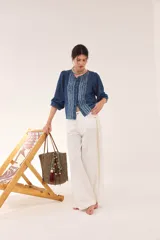 Blusa de jean fino de algodón azul, con escote a la base, mangas abullonadas y puños elásticos. Cuenta con pechera decorada con cintas superpuestas de efecto rústico y desmechado.
