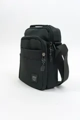 Morral de diseño compacto en color negro, con múltiples compartimentos con cierre, correa ajustable para el hombro y asa superior. Presenta un parche con logo en el frente.