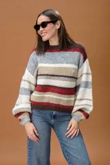 Sweater de punto con diseño de rayas horizontales en tonos marrón chocolate, rojo, beige, gris y blanco. Presenta cuello redondo y mangas largas con puños ajustados.