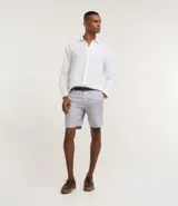 Bermuda de hombre en lino color gris claro, de corte recto, con textura discreta, bolsillos laterales y cierre frontal con botón y cremallera.