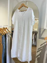 Vestido blanco de lino, corte recto, con escote en V y mangas cortas.