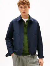 Campera azul marino de tejido técnico de Tommy Hilfiger, con cierre frontal de cremallera, cuello camisero, bolsillos laterales y parche engomado en la manga.