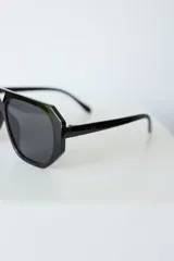 Lentes de sol con armazón de policarbonato negro y cristales tonalidad ámbar, con diseño de puente doble estilo aviador.