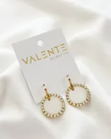 Par de aros colgantes dorados con forma circular, con centro blanco y borde con strass. Cierre tipo gancho.