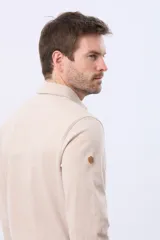 Remera polo de manga larga confeccionada en tejido jersey, con cuello clásico y cierre frontal de tres botones. Presenta un diseño liso con un pequeño logo bordado en el pecho y una etiqueta decorativa en el ruedo.