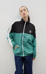 Campera de tela avión con diseño color block en negro y verde, con detalles de franjas blancas en las mangas. Presenta cierre frontal completo, cuello alto, puños y ruedo elásticos, y logo bordado en el pecho.