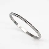 Pulsera rígida plateada de acero con cristales incrustados de circonia cúbica.