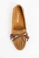 Mocasin de gamuza color camel, con detalle de flecos decorativos en la parte frontal en tonos marrón, violeta y verde agua.