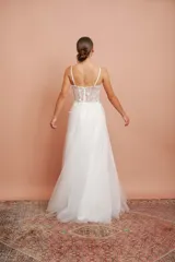 Vestido largo blanco de alta costura, con corset estructurado de tirantes finos con apliques florales y falda amplia de tul con brillo.