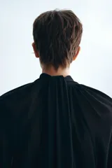 Blusa oversized negra de tejido transparente, con cuello fular, escote profundo y mangas largas con puños anchos.