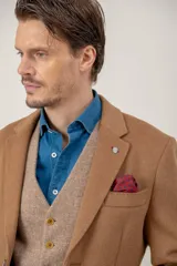 Chaquetón de lana color beige, con solapas clásicas, cierre frontal de botones y bolsillo en el pecho con pañuelo decorativo.