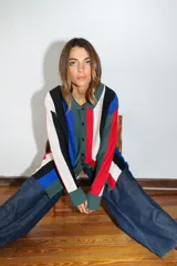 Saco tejido a máquina con rayas verticales negras y marrones, cuello camisero y botones rojos.