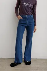 Jean de denim azul de tiro medio, con corte flare y costuras frontales destacadas.