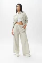 Pantalón de corte amplio y estilo piyamero, confeccionado en algodón con estampado de rayas verticales finas en color verde y blanco. Cuenta con cintura elástica y múltiples bolsillos laterales.