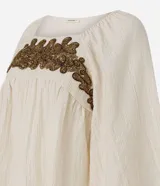 Blusa tipo bata color off-white de viscosa y poliamida, con cuello redondo, mangas cortas amplias, fruncido bajo el busto y bordado delantero contrastante.