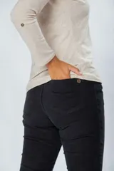 Pantalón de pana elastizada color negro, corte ajustado, cinco bolsillos y accesorios metálicos personalizados.