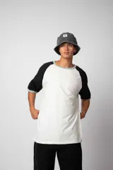Remera estilo raglán color blanco en el cuerpo, con mangas en tono tostado y ribetes en color verde militar en el cuello y los puños.