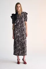 Vestido midi de corte recto con estampado animal print en tonos marrones y negros. Tiene mangas cortas abullonadas, cuello redondo y un lazo negro decorativo en el hombro.