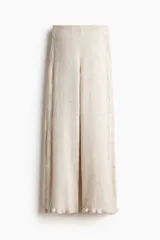 Pantalón de punto suave color beige, de tiro alto con cintura elástica, perneras rectas, secciones laterales con diseño pointelle y detalle de volados en el bajo.