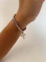 Set de dos pulseras plateadas elásticas con cuentas redondas y dije circular con una cruz calada.