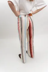 Pantalón de gabardina de tiro medio con diseño de rayas verticales en tonos rosado, rojo, celeste, beige y negro. Cuenta con bolsillos frontales aplicados y cierre con botón.