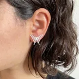 Par de aros tipo botón con forma de mariposa plateada con detalles en negro.