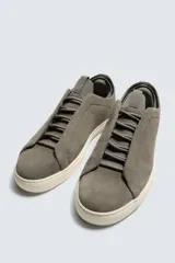Zapatilla urbana de hombre confeccionada en piel con acabado de serraje, diseño minimalista con cordonera oculta y suela de goma a contraste.