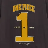 Camiseta negra de manga corta con cuello redondo y estampado frontal con el logo de la serie de anime 'One Piece' en letras amarillas.