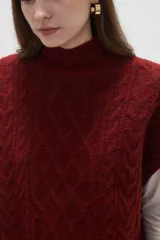 Chaleco de punto con diseño de ochos, cuello alto y corte holgado.