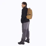 Mochila Merrell modelo Trout Basic de 25 litros, color marrón. Presenta un diseño funcional con compartimento principal con cierre, bolsillos laterales elásticos con correas de ajuste y una cinta frontal decorativa. Confeccionada en poliéster resistente con recubrimiento de PU.