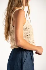Top de algodón con diseño de tejido crochet y calce al cuerpo, con breteles finos y ruedo con terminación ondulada.