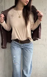 Remera manga larga de color beige, con cuello redondo y diseño bordado de flores en el hombro y lateral.