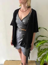 Conjunto de dos piezas color plateado brillante, compuesto por un top atado en el frente con escote en V y una minifalda cruzada con dobladillo asimétrico.