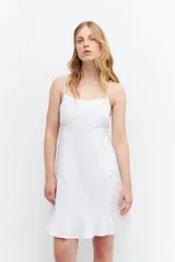 Vestido corto blanco de lino con breteles finos, corte recto y volado en el ruedo.