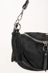 Cartera tipo bandolera de tamaño pequeño, confeccionada en material sintético con textura de gamuza en color marrón topo. Presenta un diseño semicircular con cierre superior, herrajes metálicos plateados y una correa larga ajustable de cinta técnica.
