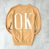 Buzo color naranja con estampa frontal de la frase "It's OK, don't worry" en color blanco.