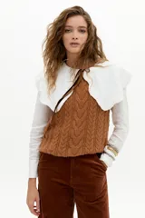 Chaleco de punto color caramelo con ochos en el frente, cuello a la base y terminaciones de rib.