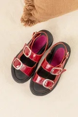Sandalias de plataforma estilo chunky en color negro, confeccionadas en material sintético efecto charol. Presentan dos tiras ajustables con hebillas metálicas plateadas y una tira trasera con hebilla para mayor sujeción. Suela dentada de goma.