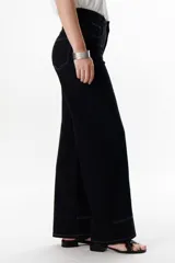 Pantalón negro de corte recto, pierna ancha y tiro alto, con detalles de pespuntes blancos a contratono.