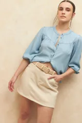 Minifalda de jean color beige claro, con corte en A y bolsillos delanteros curvos.