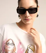 Remera de algodón color blanco con estampado de figuras femeninas de colores. Tiene cuello redondo y mangas cortas.