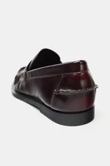 Mocasín de mujer con acabado acharolado en color bordó, diseño con antifaz, detalle de fruncido frontal y suela plana.