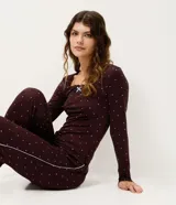 Blusa de pijama de manga larga color bordó con estampado de pequeños corazones blancos. Presenta escote en U con detalle de encaje y un pequeño moño celeste en el centro.