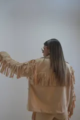 Campera color beige de gamuza sintética con flecos en mangas, espalda y ruedo.