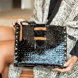 Cartera de cuero vacuno negro con textura tipo cocodrilo, cierre superior y bolsillo trasero con cierre. Tiene correa larga ajustable, interior forrado con bolsillo para celular y apliques metálicos dorados.