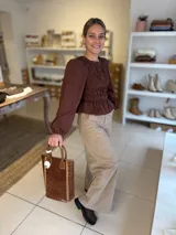 Blusa color chocolate con diseño de frunces elásticos en el frente y la espalda, mangas largas abullonadas con puños elásticos y corte peplum.