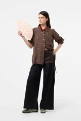 Camisa de lino color chocolate, de corte relajado y mangas largas con detalles bordados florales en contraste. Cuenta con cuello clásico y cierre frontal de botones.