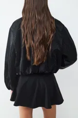 Campera bomber de textura satinada con cierre frontal de cremallera, cuello redondo y mangas largas con puños elásticos.