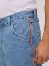 Bermuda de jean de mezclilla negra con efecto lavado, corte recto y costuras en contraste de hilo blanco. Presenta un parche bordado con el logo "Rusty" en color celeste en el bolsillo trasero derecho.